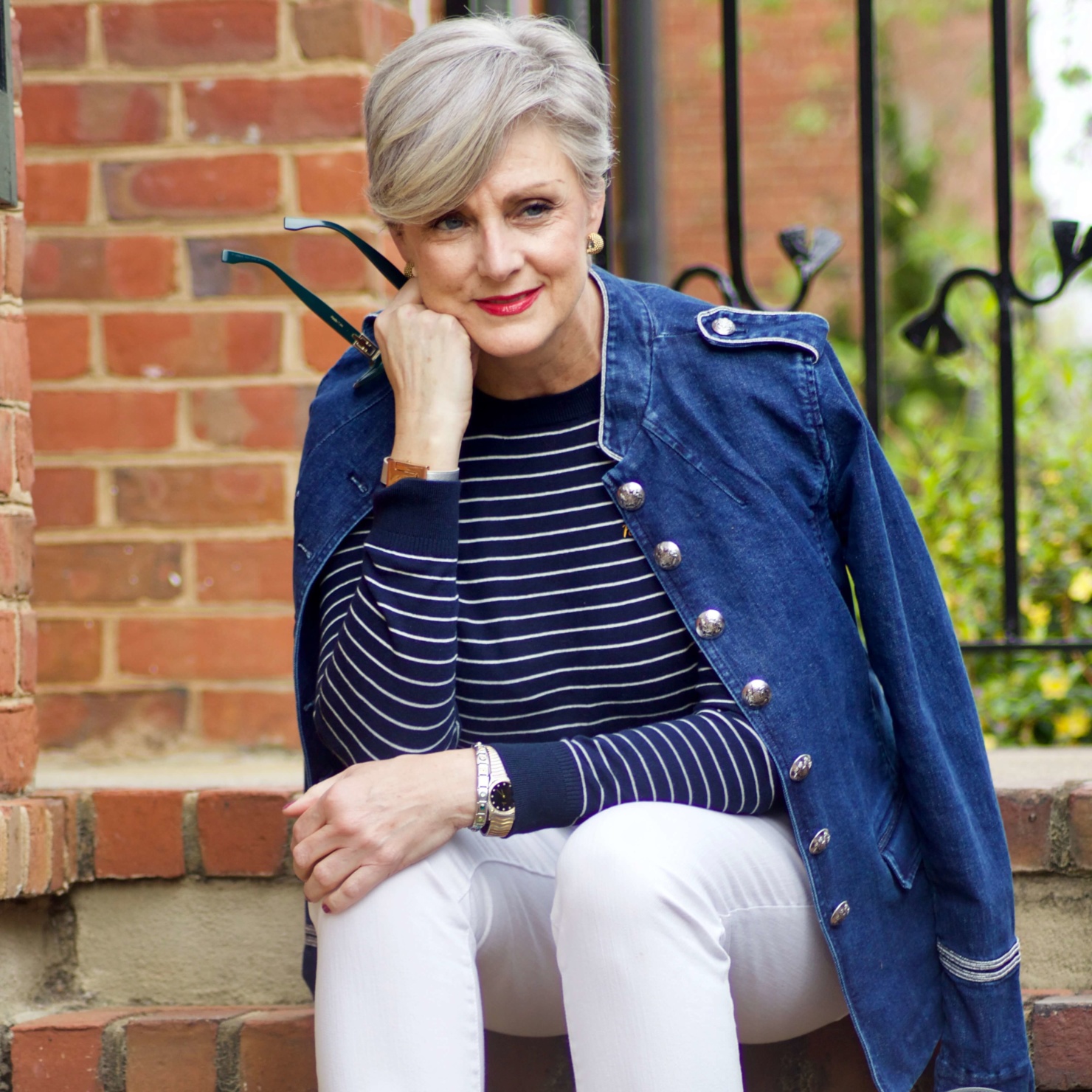 beth from Style at a Certain Age wears a denim military jacket, striped sweater, and white denim