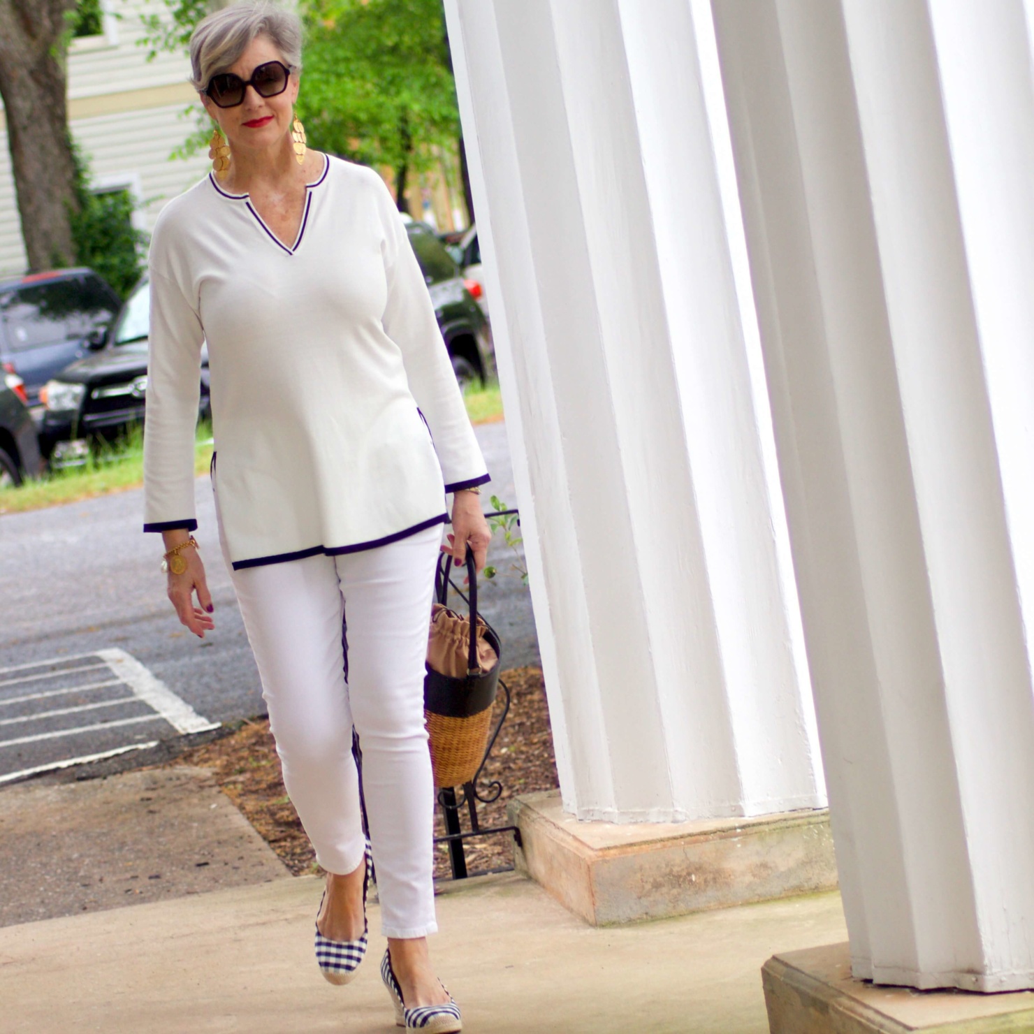 beth from Style at a Certain Age wears a monochromatic white outfit. white tunic trimmed in blue, white jeans and gingham espadrilles
