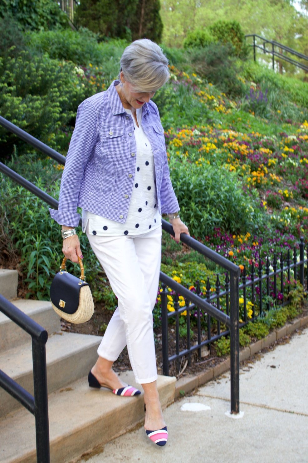 beth from Style at a Certain Age wears a gingham jean jacket, polka dot top, white chinos and wicker handbag