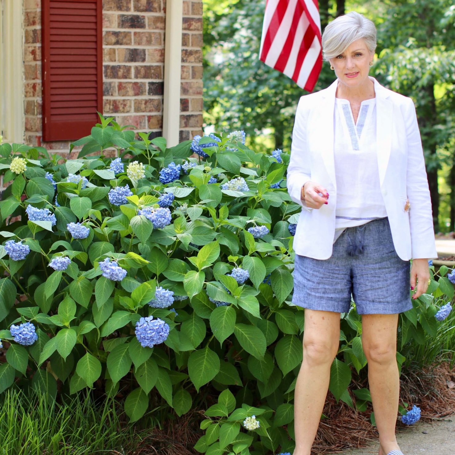 beth from Style at a Certain Age wears a classic summer blazer, drawstring shorts, seersucker sandals, and striped linen top