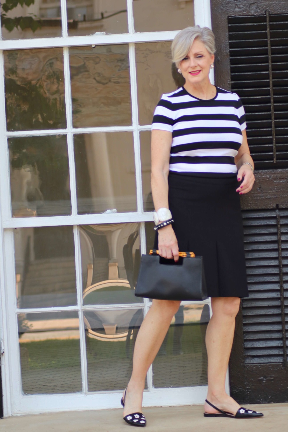 beth from Style at a Certain Age wears a black and white tee, black a-line skirt, pointy toed flats and black handbag