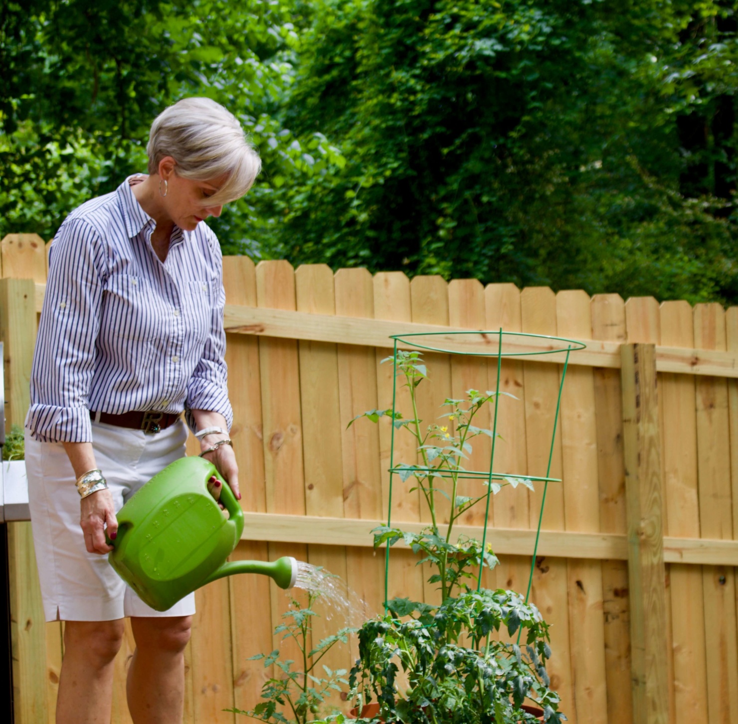 beth from Style at a Certain Age wears a striped shirt, white shorts, sandals, and rattan handbag