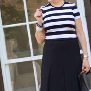 beth from Style at a Certain Age wears a black and white tee, black a-line skirt, pointy toed flats and black handbag