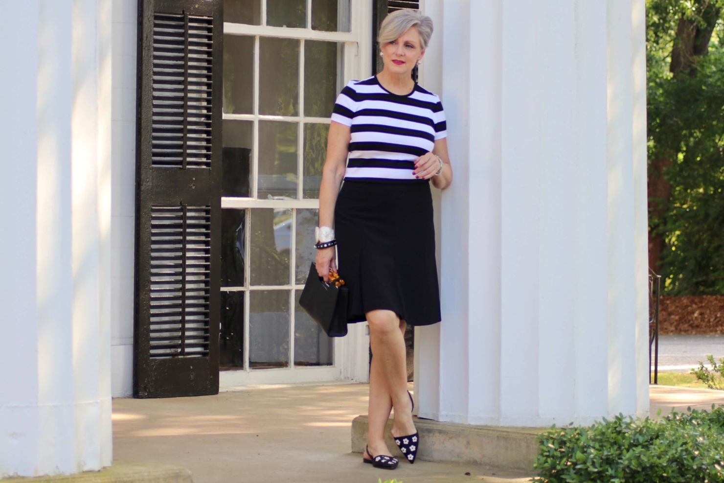 beth from Style at a Certain Age wears a black and white tee, black a-line skirt, pointy toed flats and black handbag