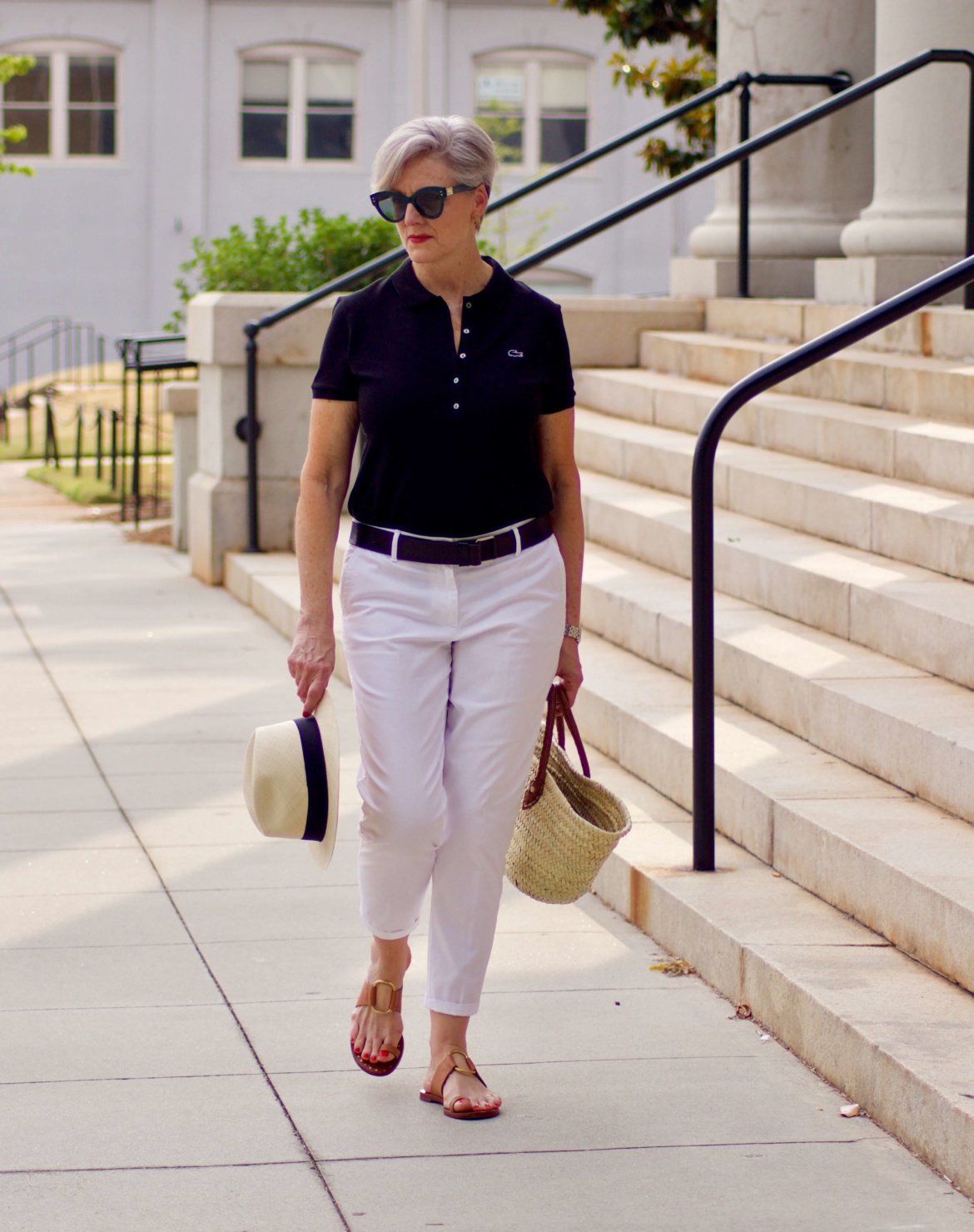 lacoste black polo, white chinos, brown sandals, straw tote