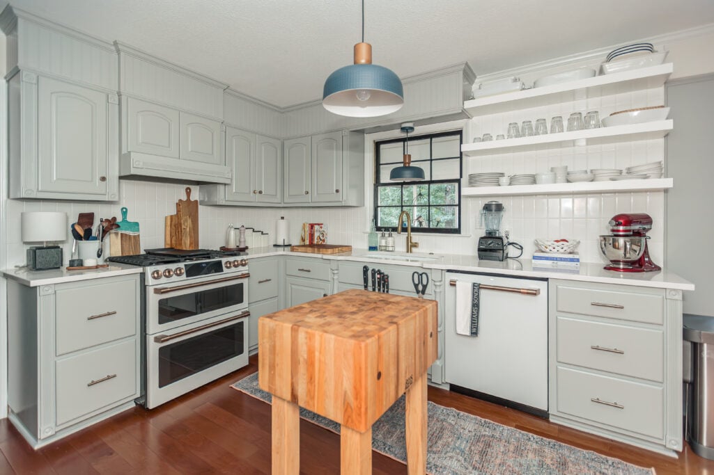 White butcher block island on wheels with wood countertop, books, and wicker storage basket — timeless 2025 kitchen remodel idea.