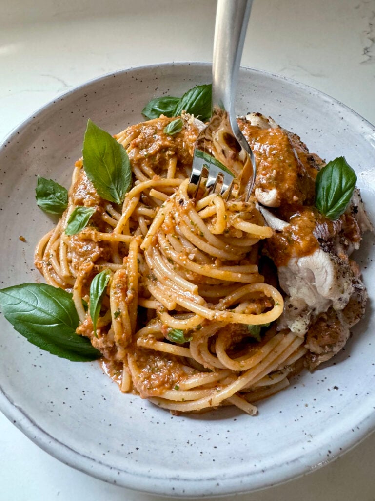 Close-up of the finished pesto pantesco in the food processor bowl, showing a smooth, rusty-orange sauce with flecks of herbs