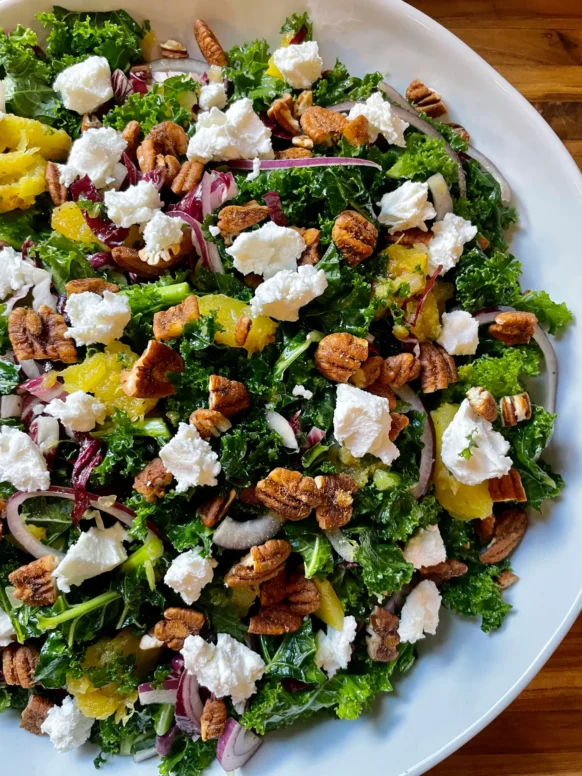 Kale salad with roasted acorn squash, cranberries, and pecans in a large bowl