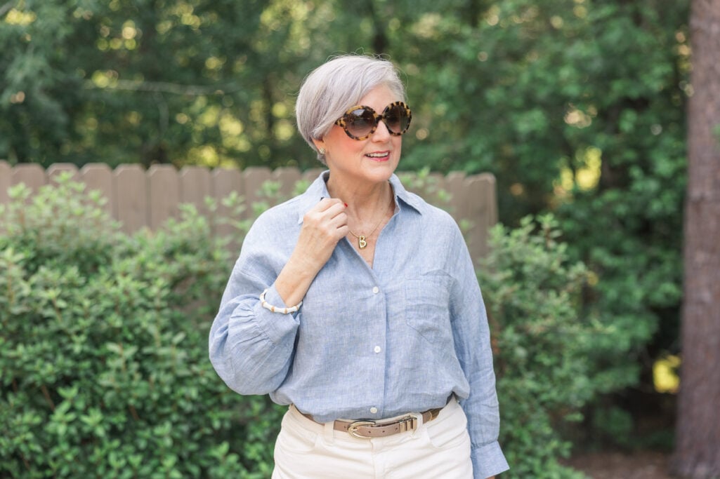 Woman over 50 in loose Madewell chambray blouse and belted ivory pants