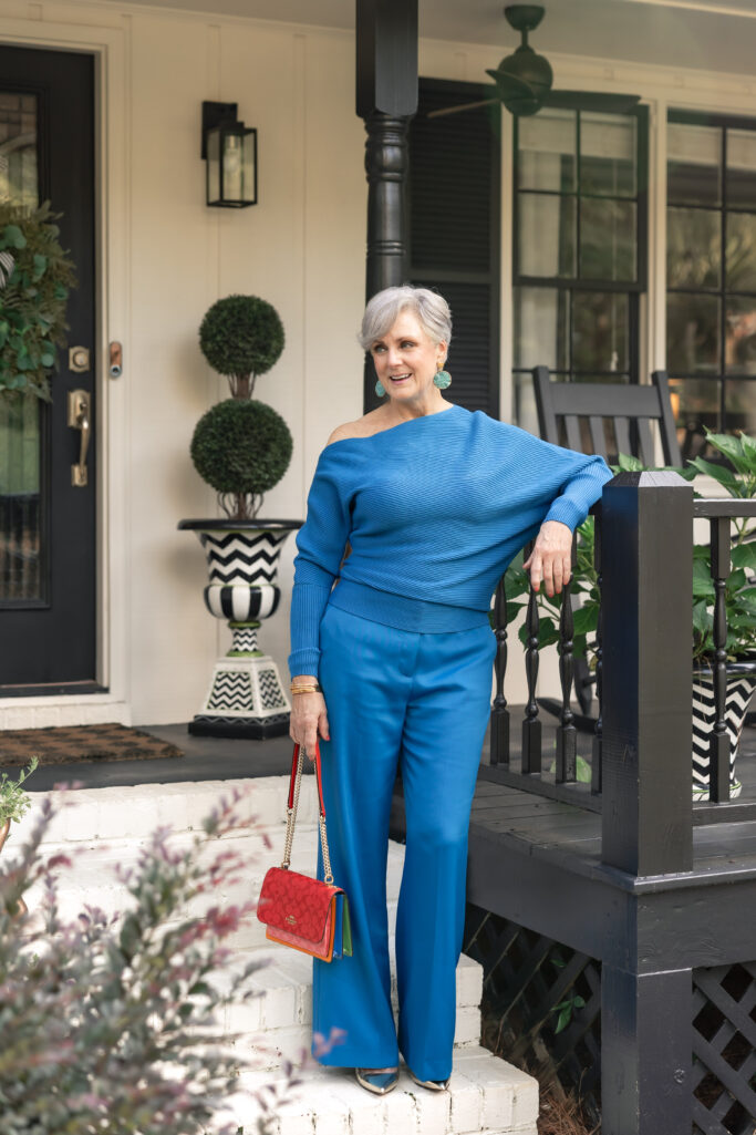 Woman in cobalt monochrome outfit with off-shoulder sweater and wide-leg trousers.