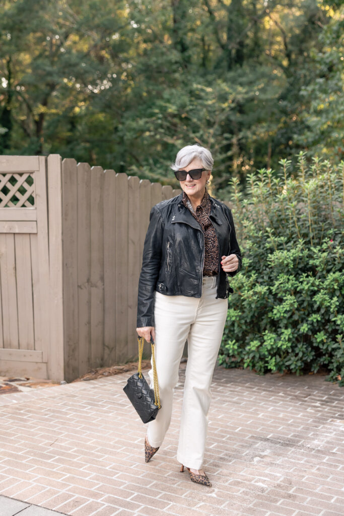Stylish woman in black leather jacket, cream jeans, and leopard heels.