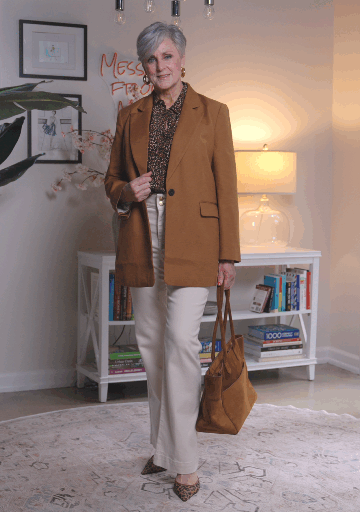 Woman over 50 wearing camel blazer, leopard blouse, and high-waist denim, chic fall outfit