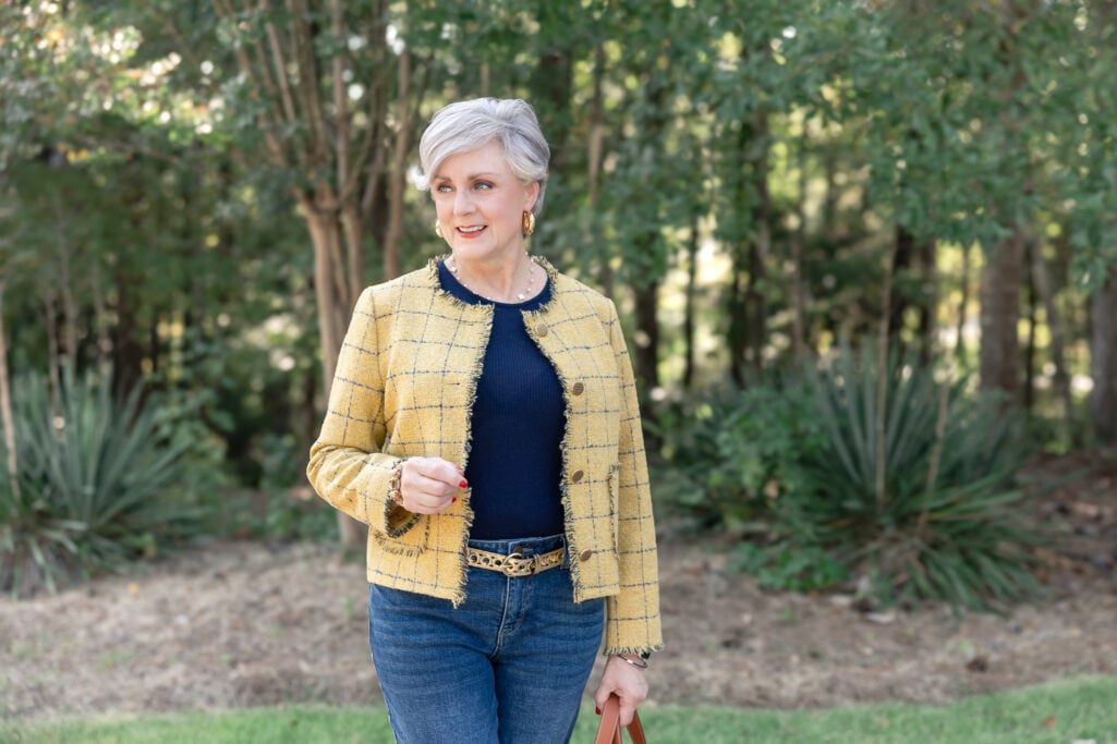 Elegant over-50 fall outfit idea with a yellow tweed blazer, navy top, straight-leg jeans, and metallic flats. Golden Moments Golden Bachelor
