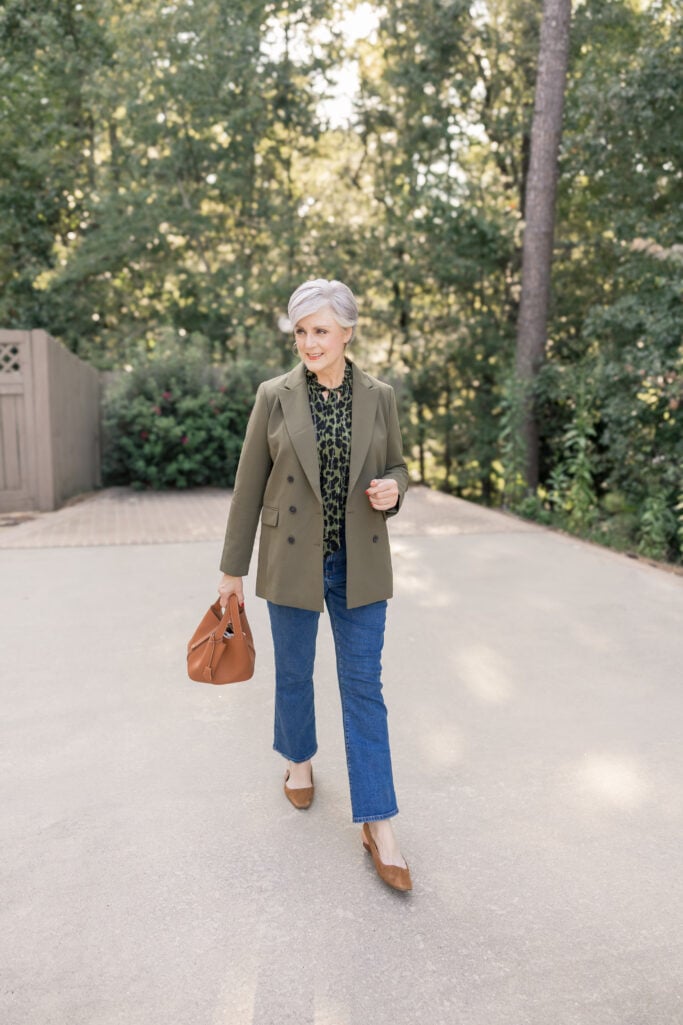 Beth Djalali in olive blazer, leopard blouse, straight-leg jeans, and tan accessories—classic fall outfit idea for women over 50.