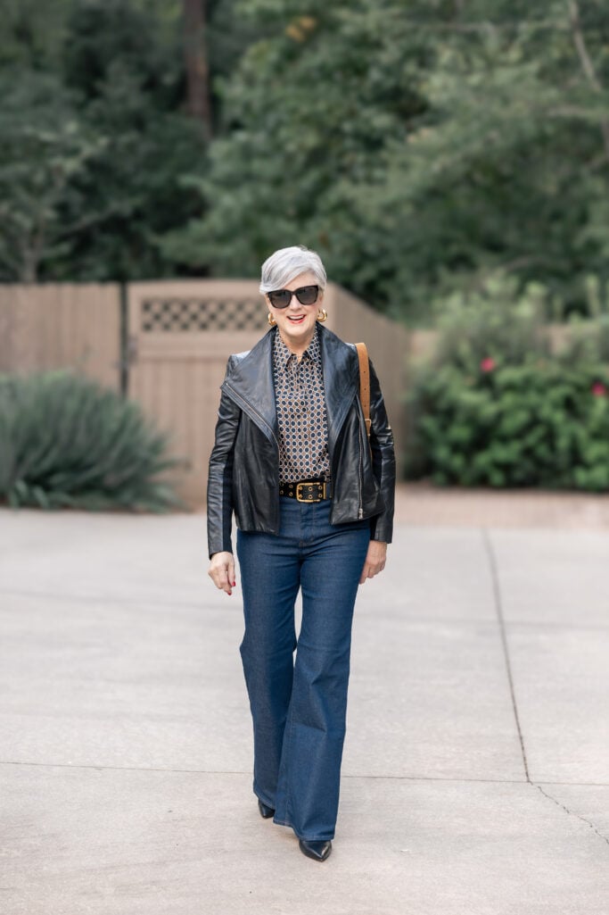 Beth Djalali in black leather jacket, flare jeans, and patterned blouse—edgy fall outfit idea for women over 50.