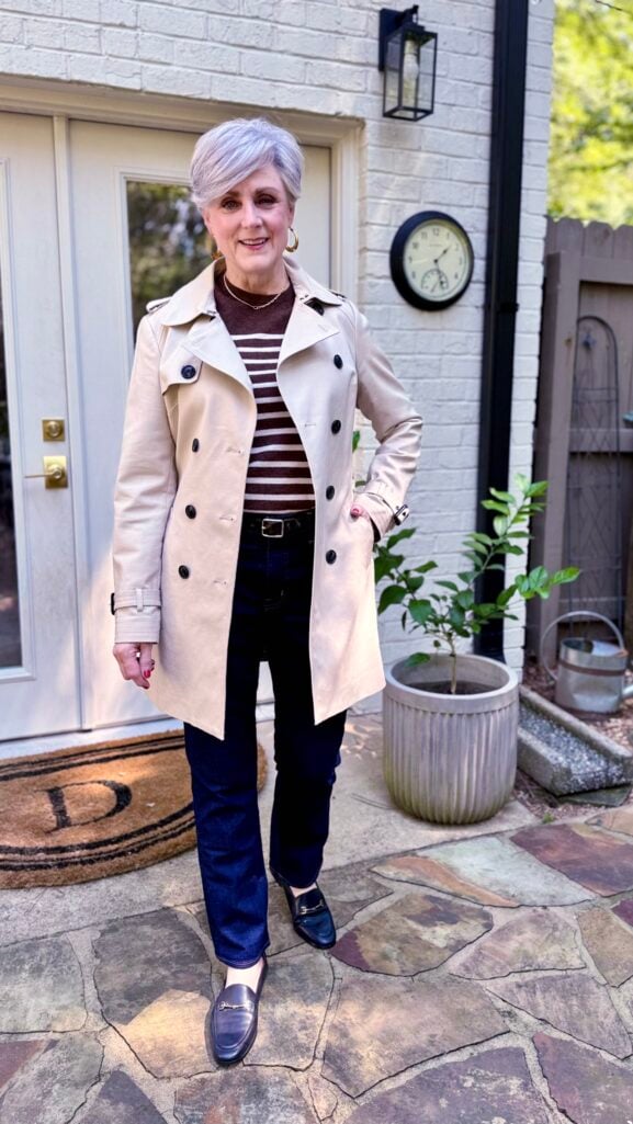 Khaki trench coat layered over straight-leg jeans for timeless style
