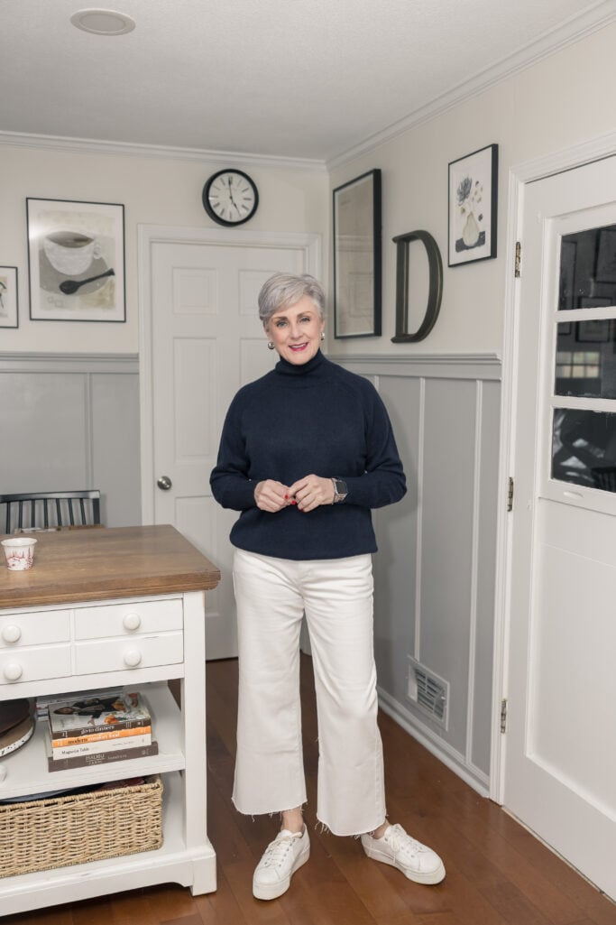 Beth Djalali in navy turtleneck and white jeans with sneakers—casual fall outfit for women over 50.