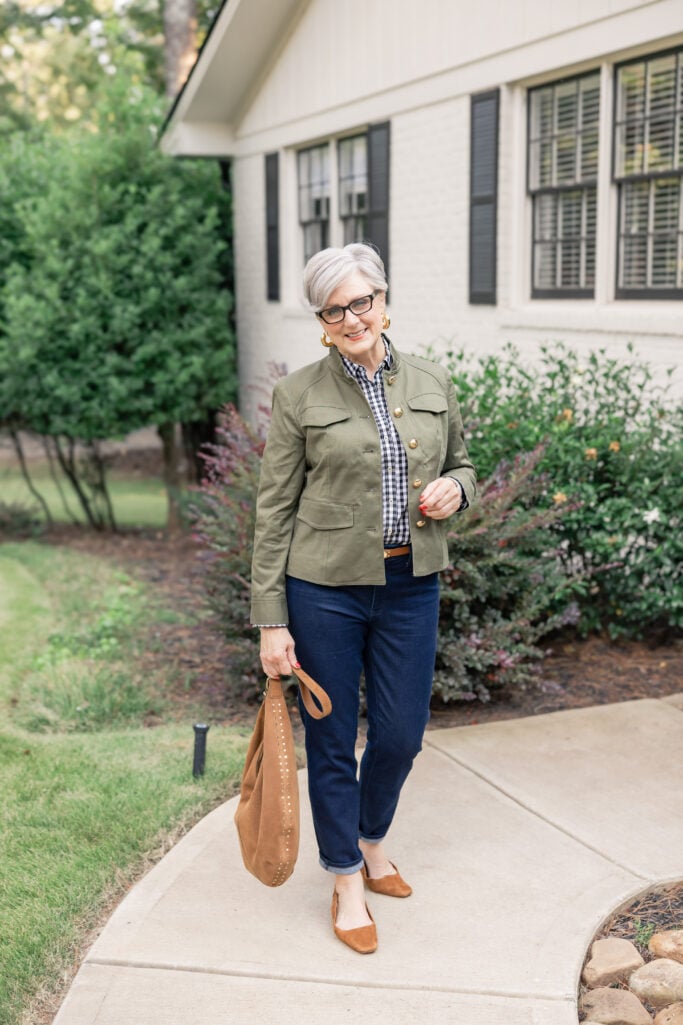Woman styling deep indigo denim with an olive twill jacket with camel suede accessories.
