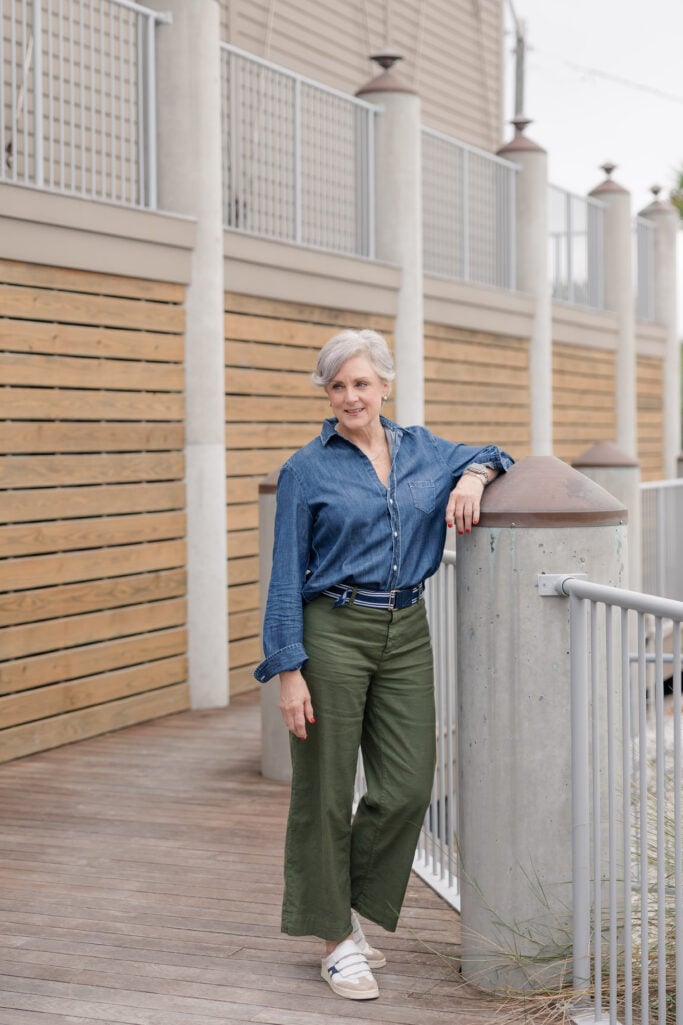 Over 50 woman wearing a dark denim shirt and wide leg pants.