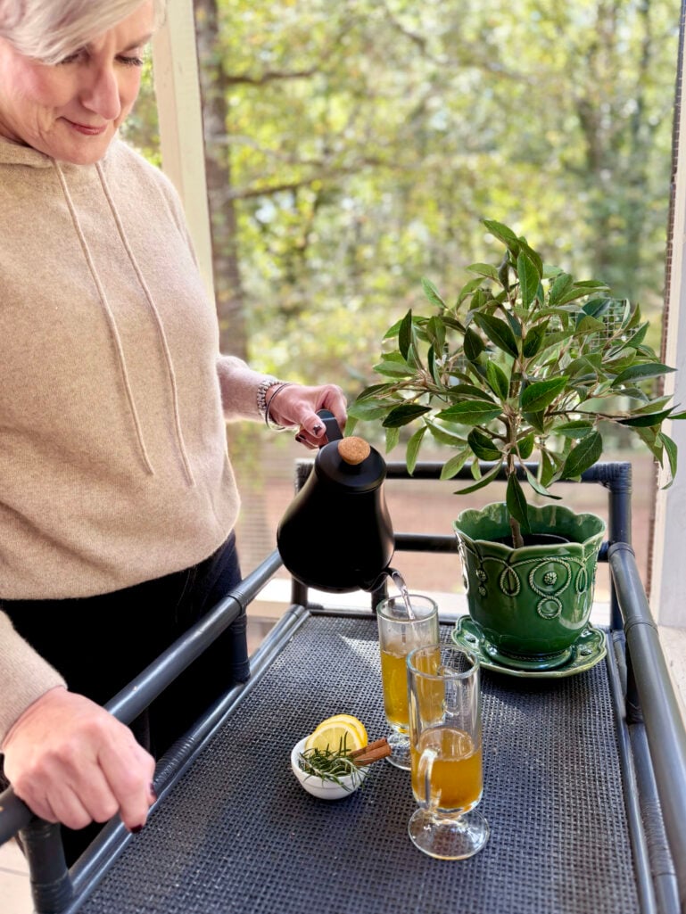 woman pouring hot water into a hot toddy cocktail