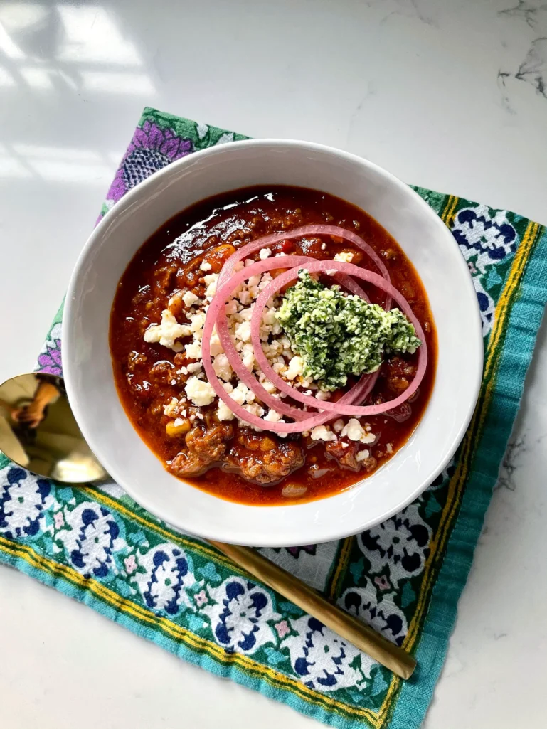Instant Pot Chili in bowl with toppings – Hearty chili topped with cotija cheese, pickled onions, and cilantro.