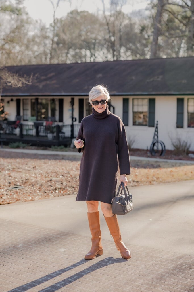 Over 50 Woman wearing a cozy sweater dress with tall riding boots
