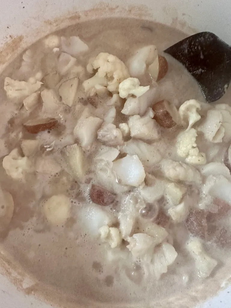 Simmering dairy-free seafood chowder with cod, cauliflower, and red potatoes in creamy cauliflower-based broth