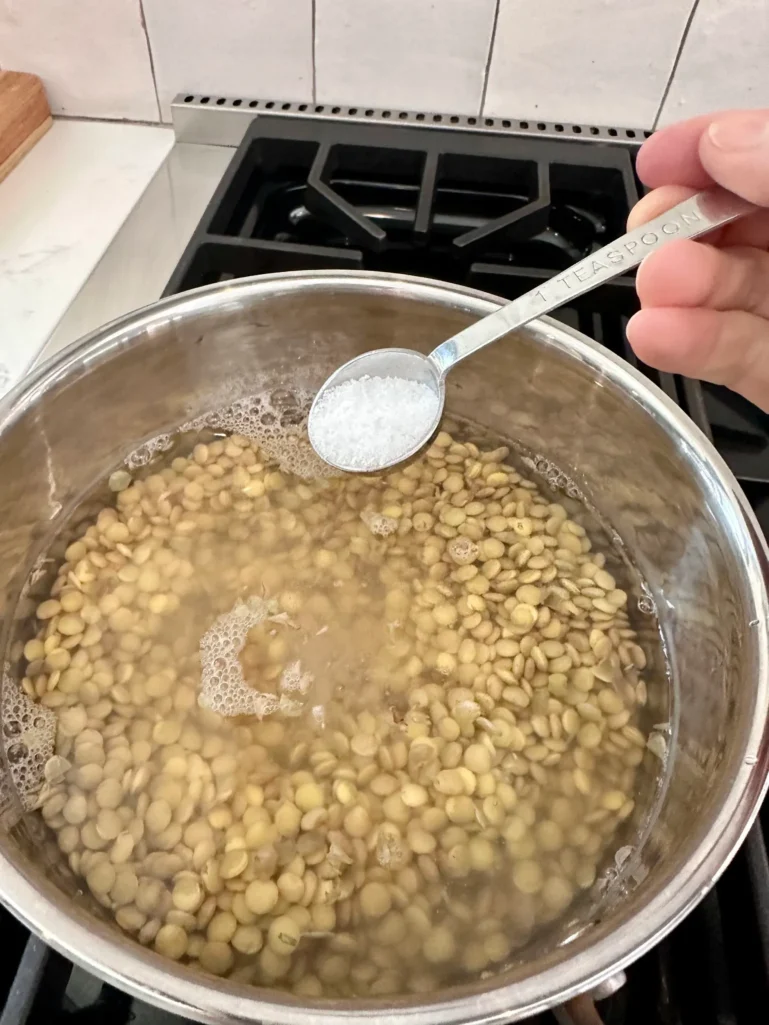 Brown lentils soaking in salted water in saucepan - how to prepare lentils for salad