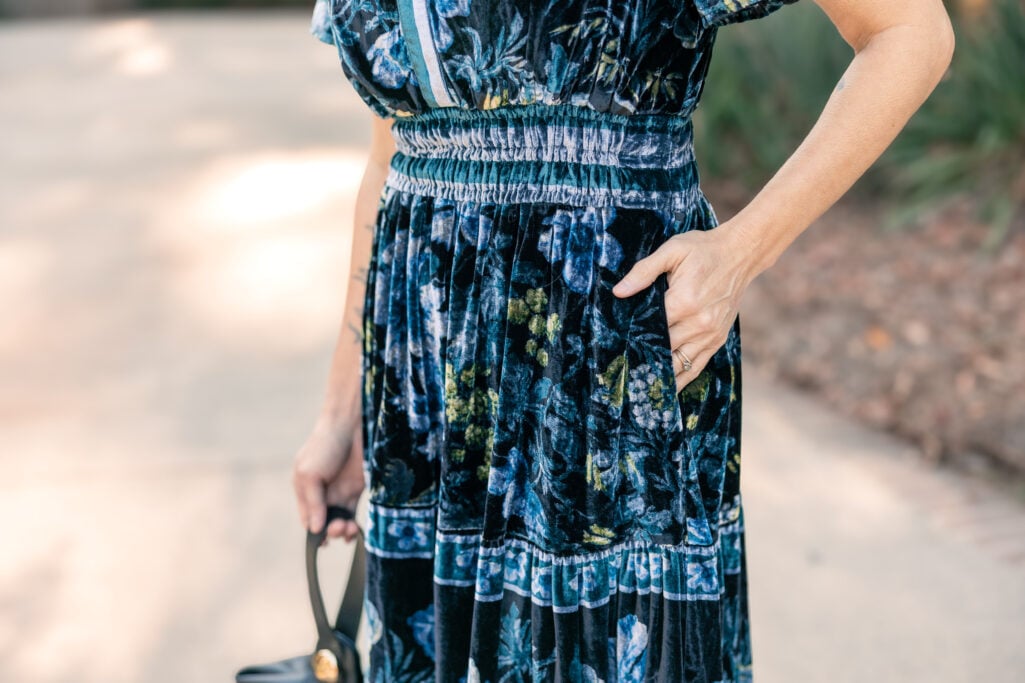 Close-up detail of navy velvet maxi dress showing smocked waist with hand in pocket - petite dress proportion