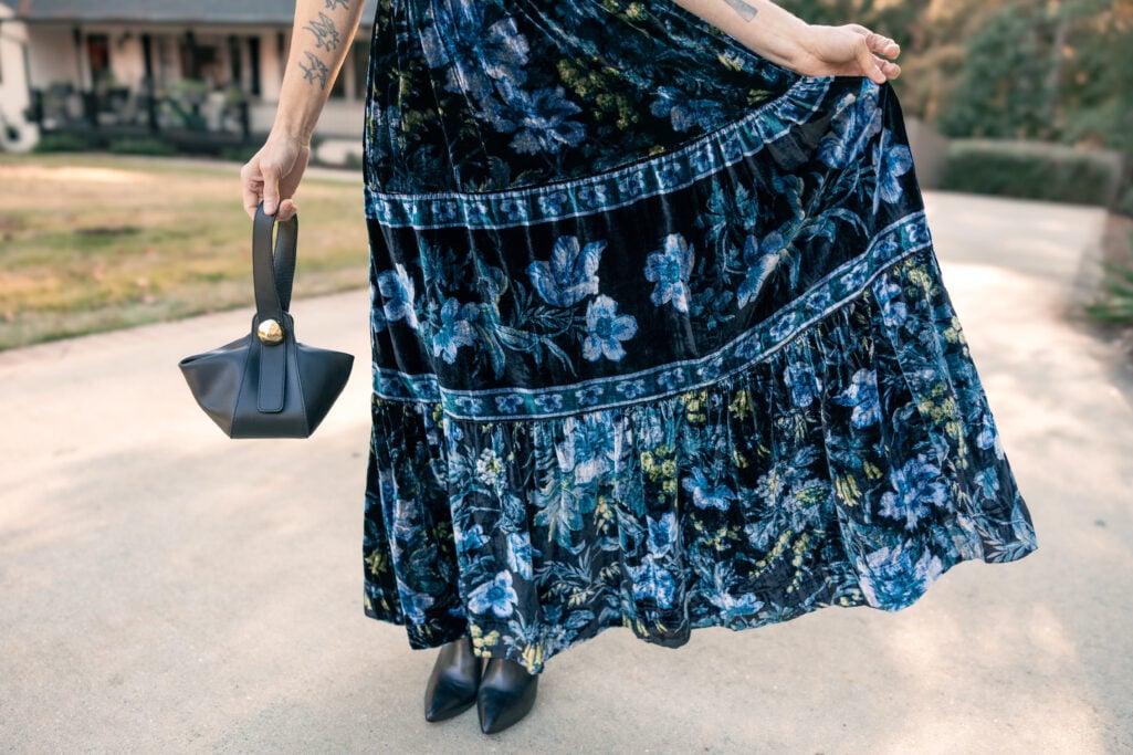 Detail of navy velvet maxi dress showing tiered skirt volume and blue floral print pattern - petite occasion dress