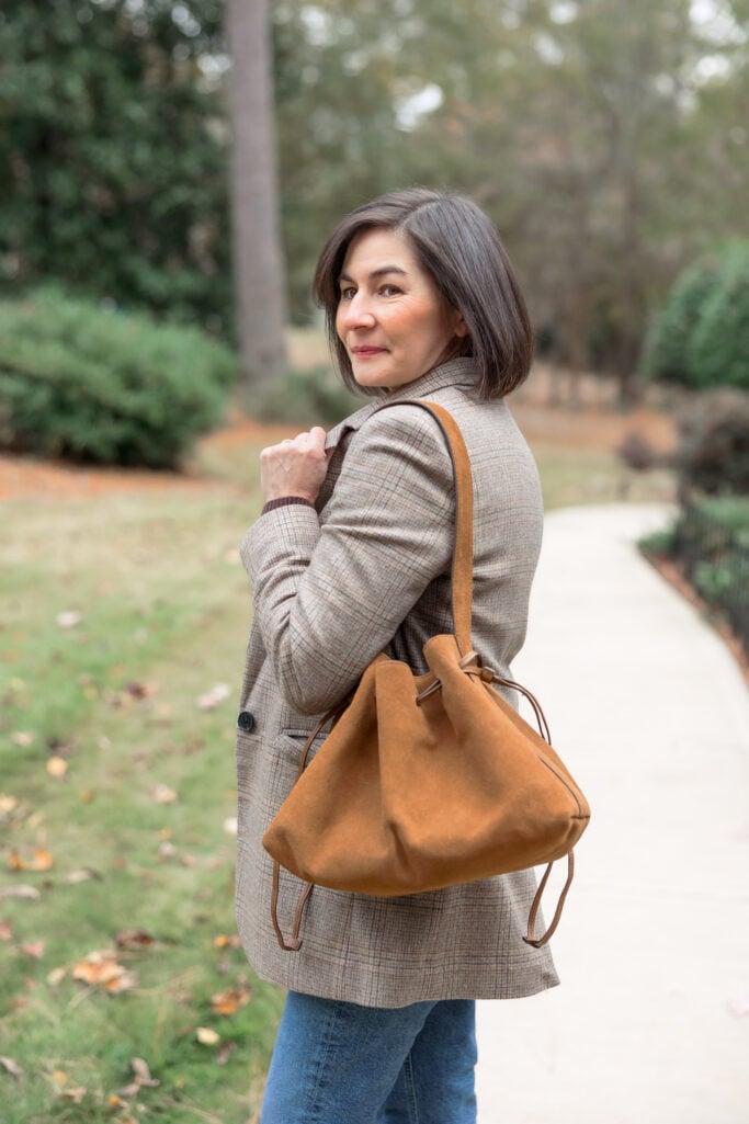 Close up of tan suede Madewell drawstring shoulder bag showing drawstring closure detail and leather quality