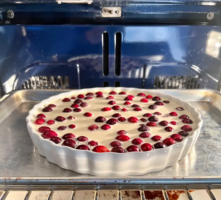 Cranberry clafoutis baking in the oven on a sheet tray