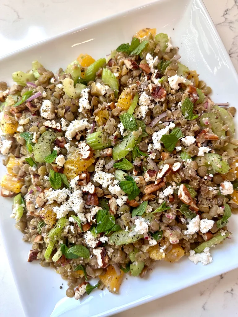 Finished lentil salad with oranges feta toasted pecans and fresh mint on white platter - healthy Mediterranean recipe