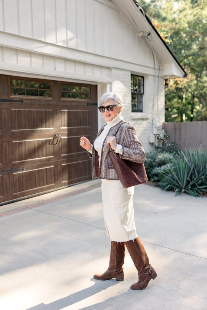 Beth Djalali wearing cream denim midi skirt with brown suede knee-high boots, white turtleneck, and houndstooth blazer - equestrian chic winter outfit