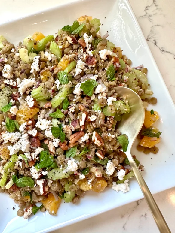 Lentil salad with oranges feta cheese toasted pecans and fresh mint on white serving platter - Kelly's Kitchen recipe