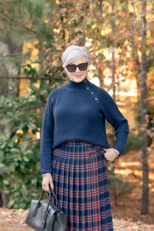 Beth Djalali wearing navy ribbed turtleneck sweater with navy plaid midi skirt and black accessories - best boots to wear with skirts for women over 50