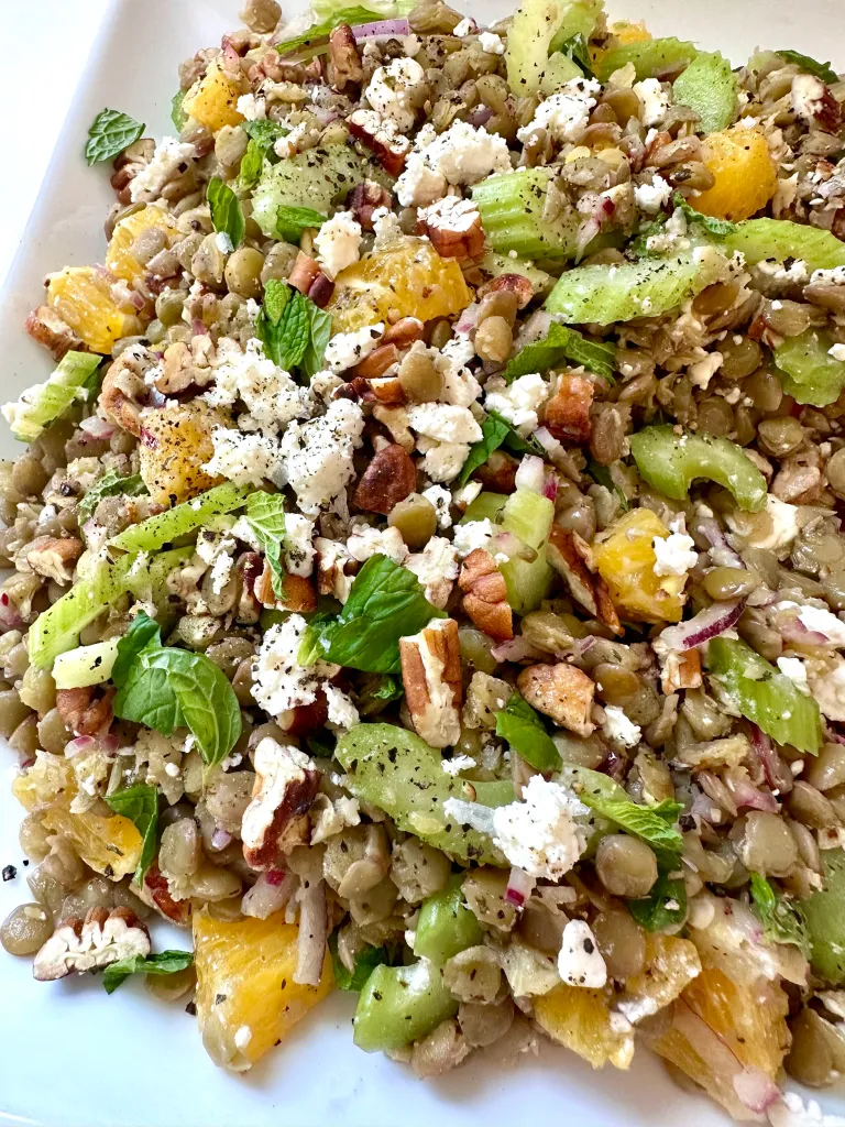 Lentil salad with oranges feta cheese toasted pecans and fresh mint on white serving platter - Kelly's Kitchen recipe