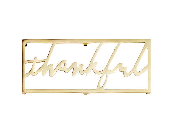 Brass trivet with thankful inscribed in the middle. Sleek and modern pot holder in a warm gold tone for a festive Thanksgiving tablescape