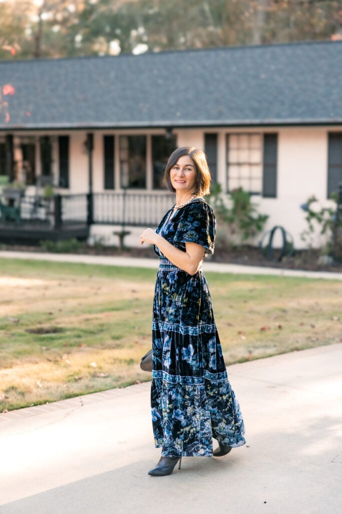 Kelly Djalali wearing a blue velvet floral maxi dress with black knee-high boots - romantic winter wedding guest outfit