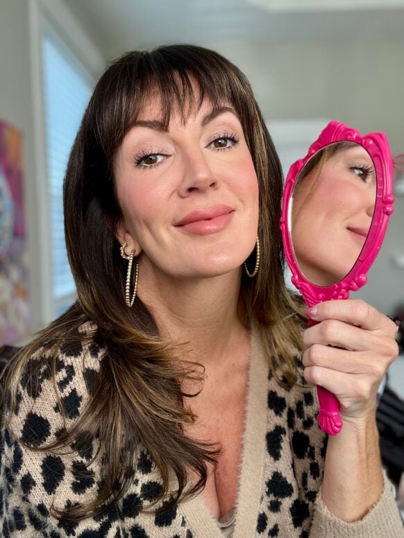 Jennifer with full makeup over skincare routine holding pink mirror showing finished look - smooth skin over 40 with makeup