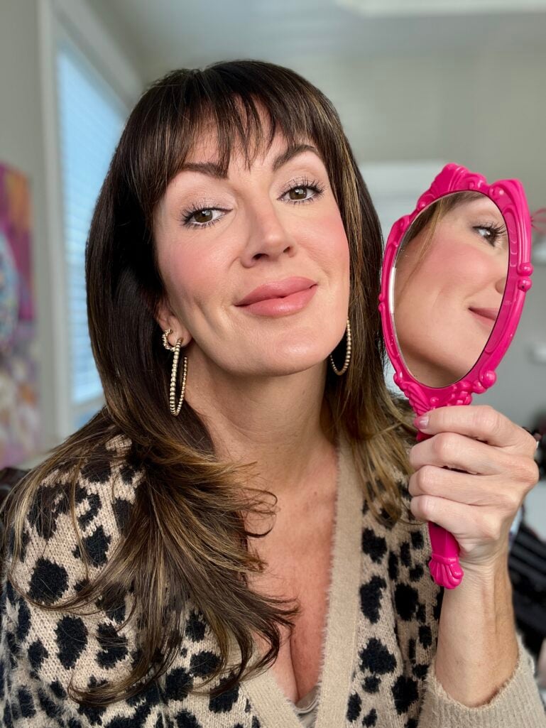 Jennifer with full makeup over skincare routine holding pink mirror showing finished look - smooth skin over 40 with makeup
