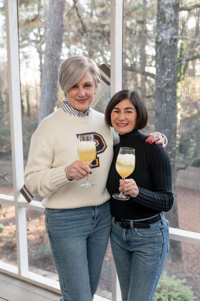 Beth and Kelly raising Prosecco punches on the screened porch, Beth in her cream P sweater and Kelly in her black cashmere turtleneck