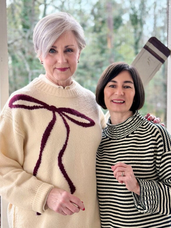 Beth and Kelly smiling together on the porch in their cozy winter sweaters
