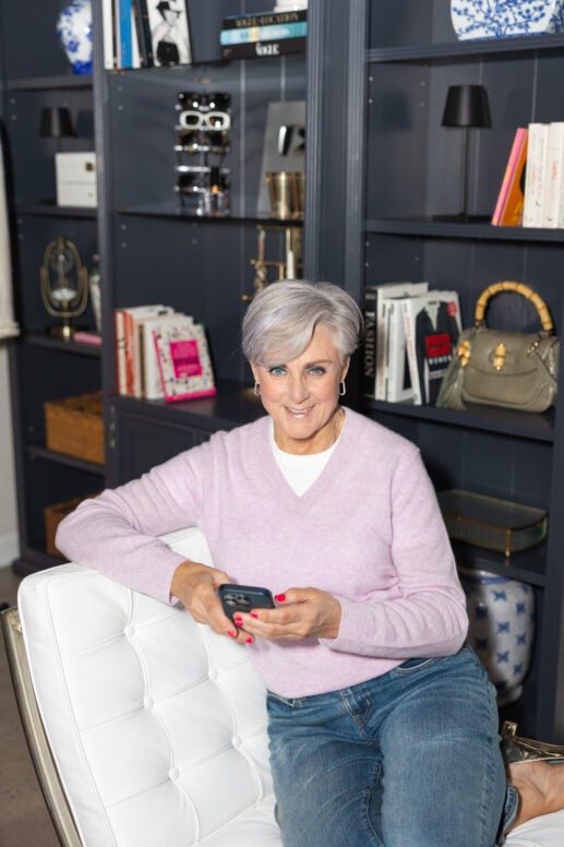 Woman over 50 sitting on a chair with her phone, ordering items online for cyber monday