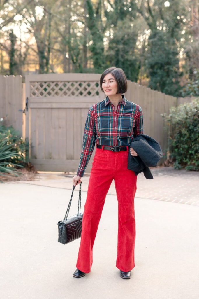 Full length action shot of Kelly in red corduroy pants holiday outfit showing how wide-leg flare pants move and fit on petite frame