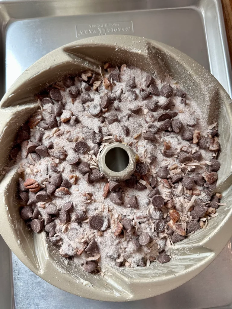 Unbaked coffee cake in bundt pan topped with chocolate chip streusel on a sheet tray