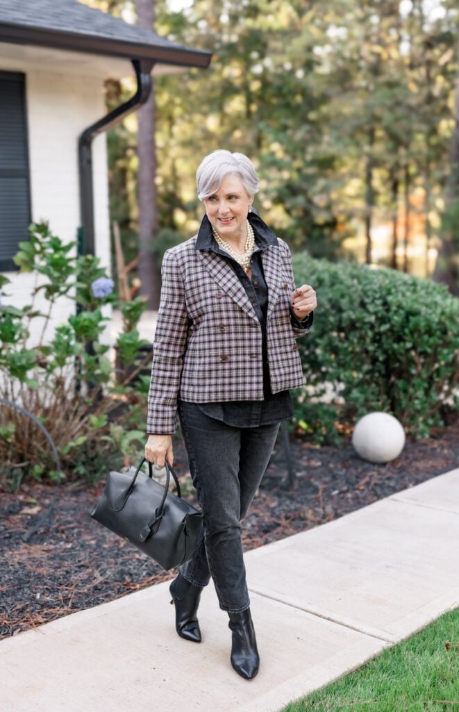 Beth wearing a lavender and gray Pemberley plaid blazer over a black denim shirt with straight leg jeans, black pointed-toe kitten heel boots, multi-strand pearls, and black leather satchel—non-traditional holiday plaid outfit over 50