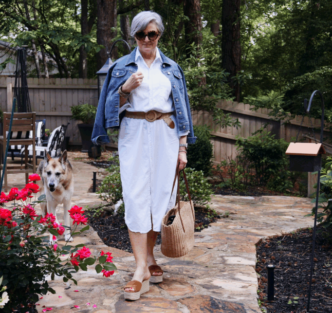 Coastal grandmother style outfit with white linen shirt, tan trousers, and straw tote for women over 50