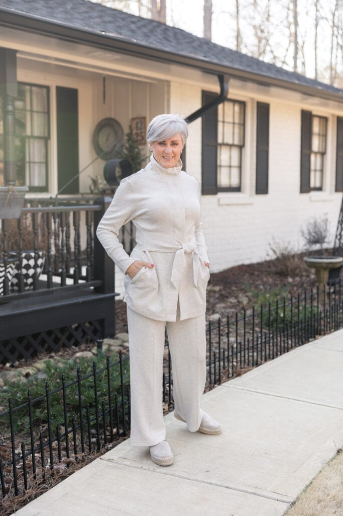 Woman in cream athleisure jacket and wide leg pants with sneakers