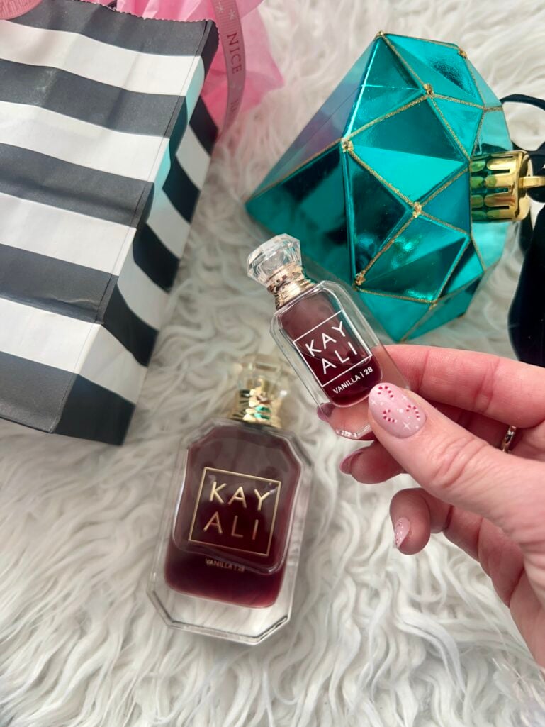 Flatlay of Kayali Vanilla 28 perfume bottles with Sephora striped gift bag and teal ornament gift box